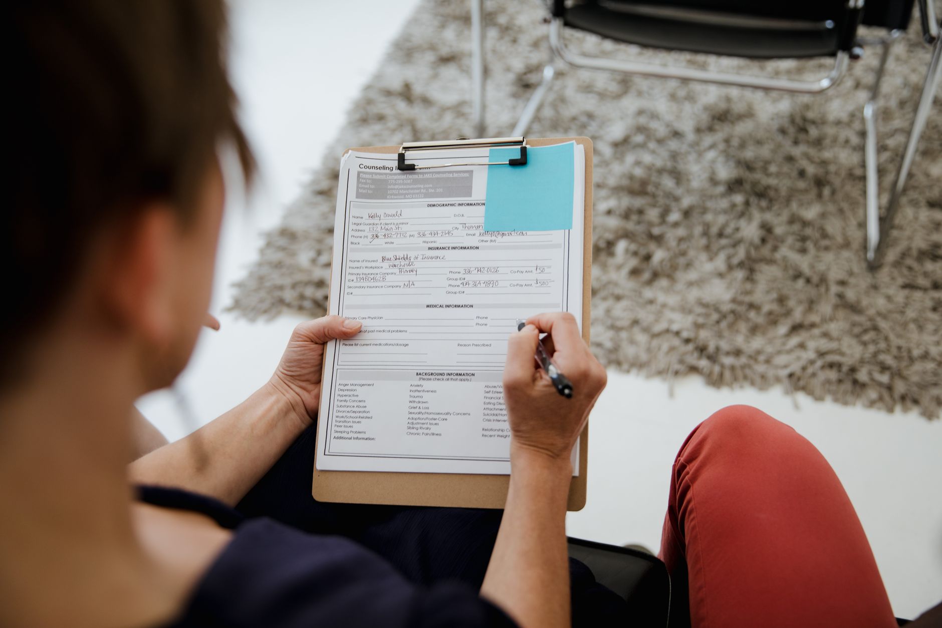 woman filling out paperwork with dog beside her at desk