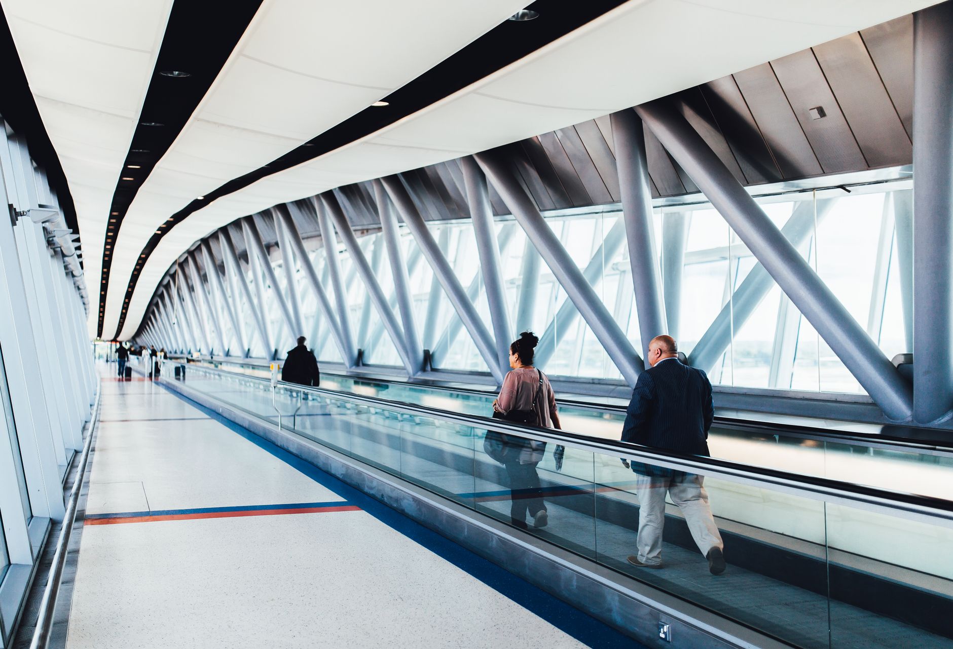 passenger rolling pet stroller through airport terminal corridor