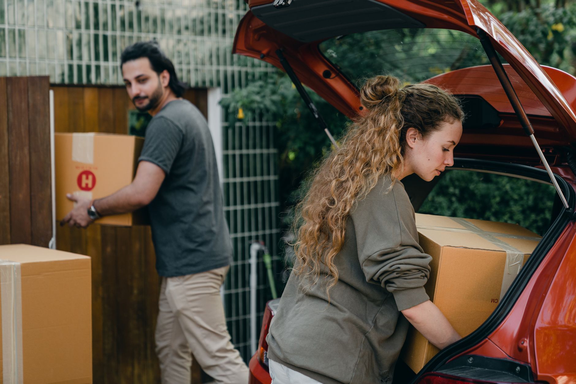 person loading dog crate into car trunk driveway moving boxes