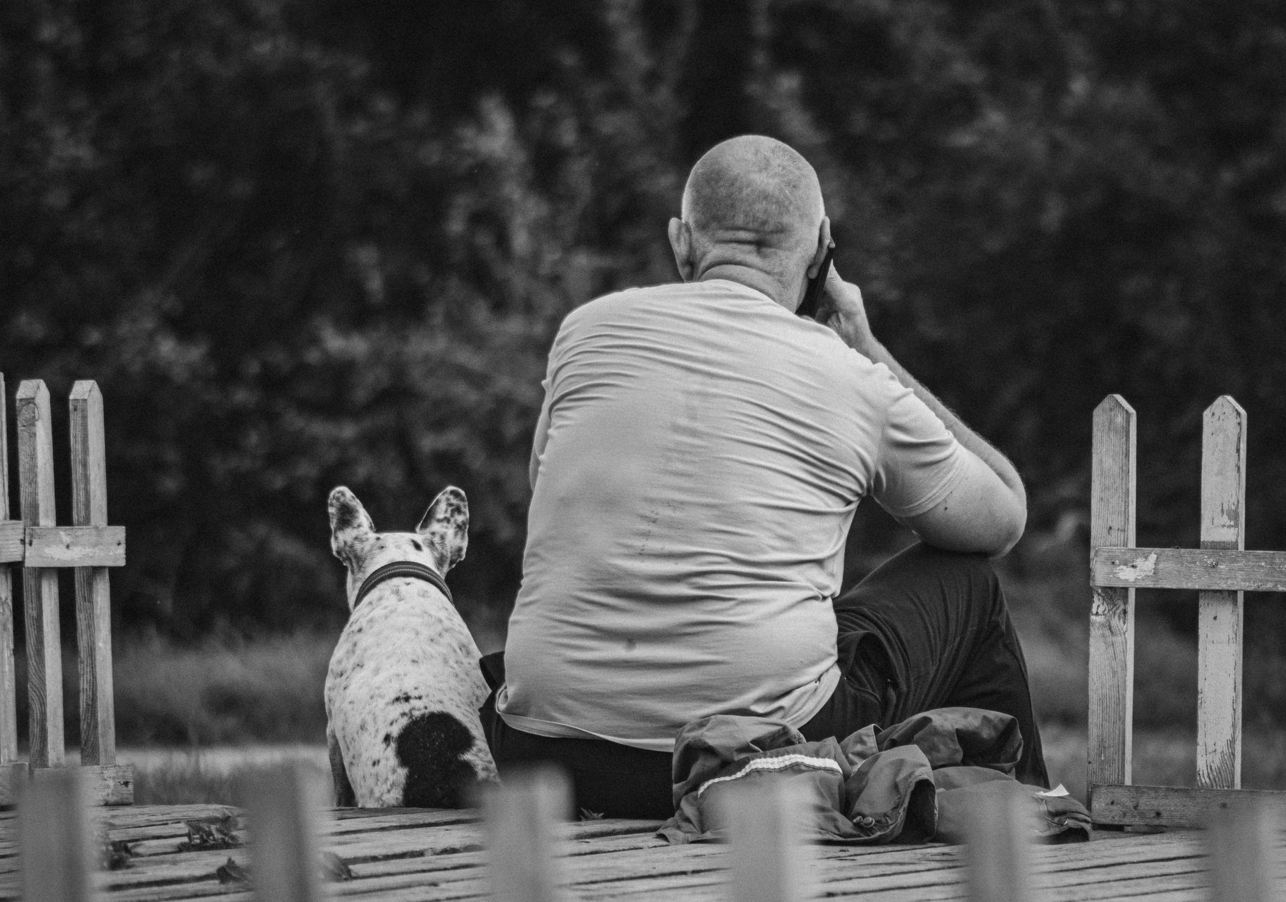 farmer holding phone photographing dog outdoors in rural setting
