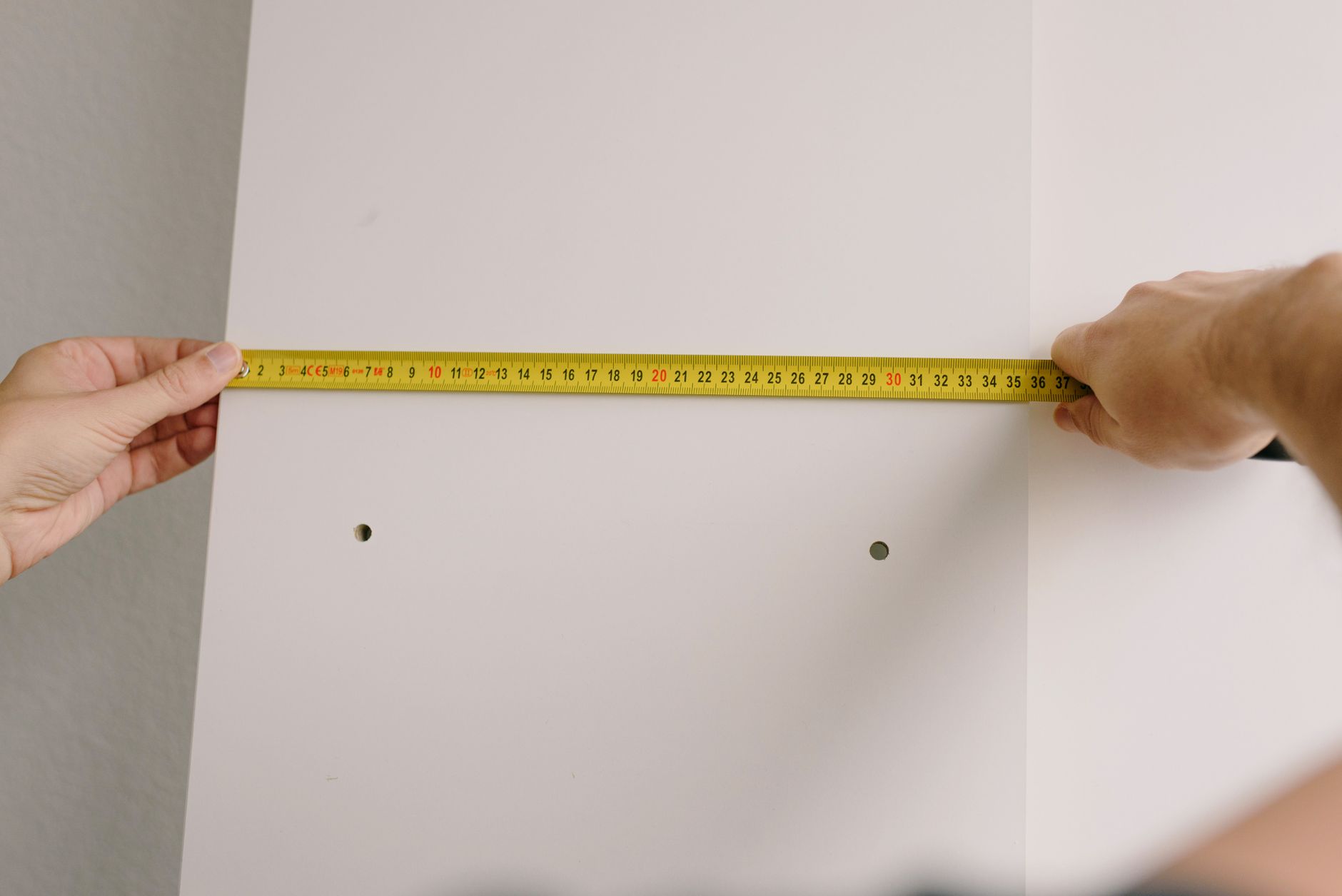 dog owner measuring terrier with tape measure beside travel crate at home