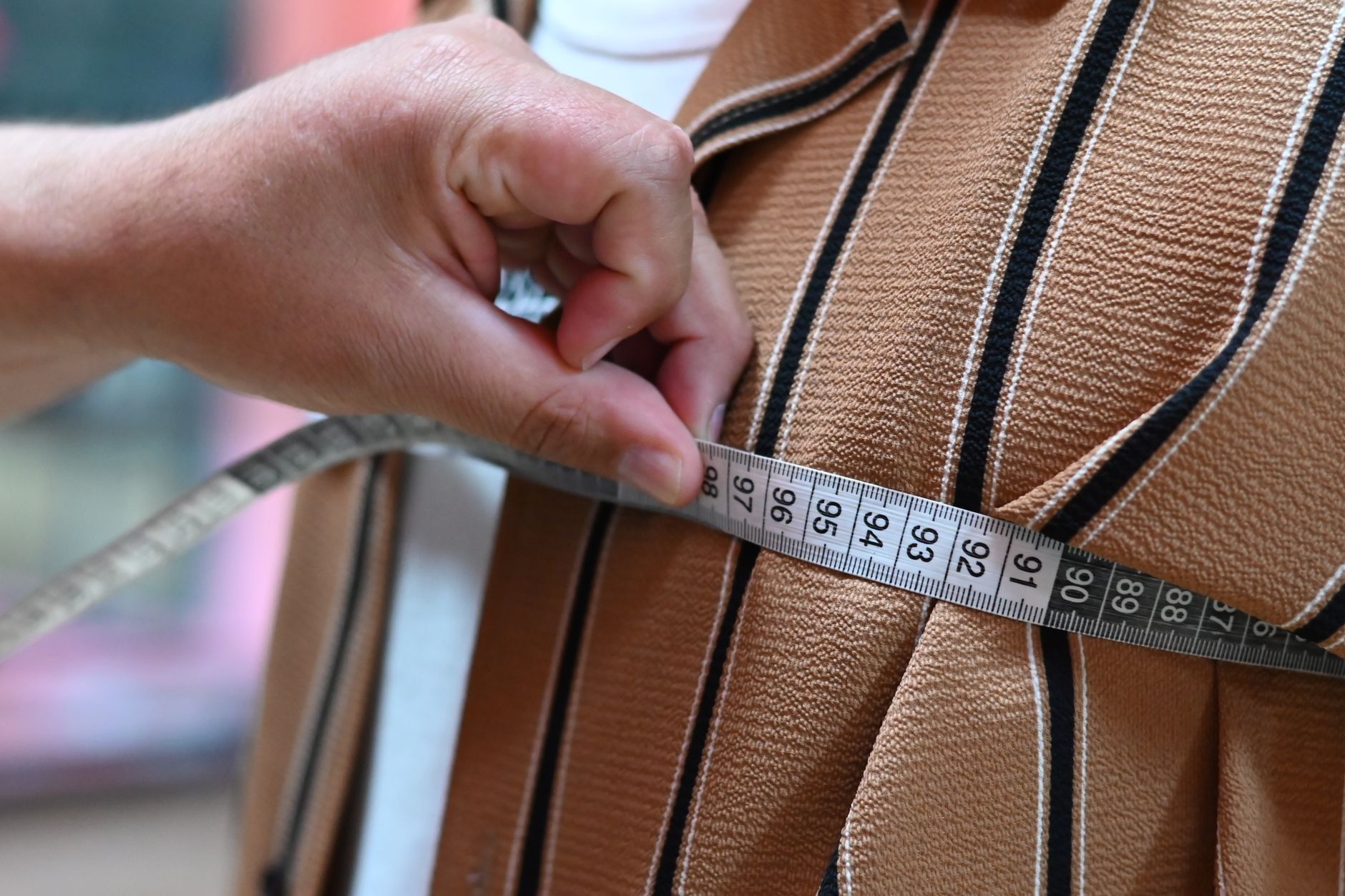 woman measuring pet carrier with tape measure at airport check-in