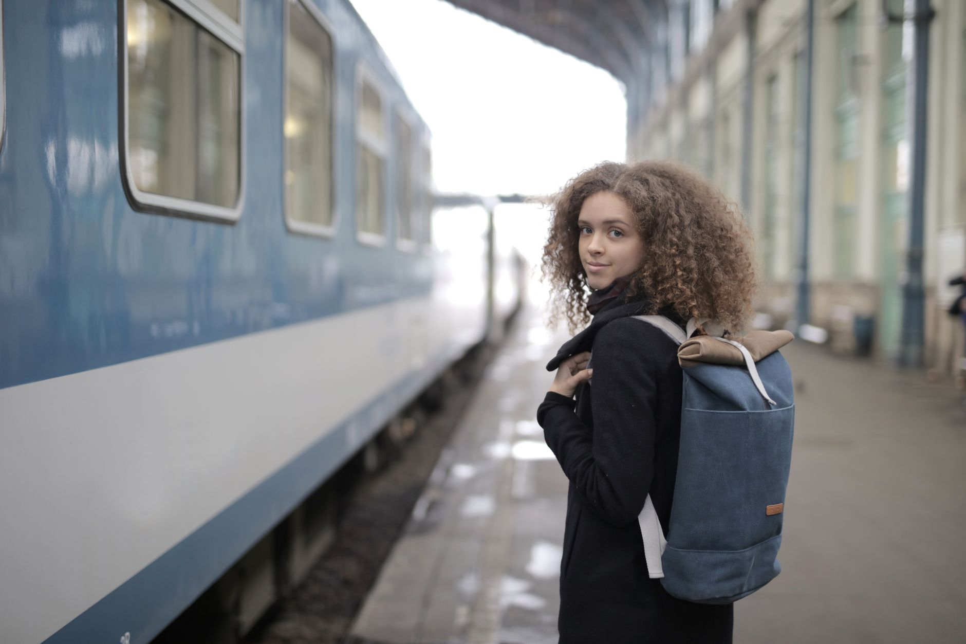 dog peeking out of backpack carrier on train platform