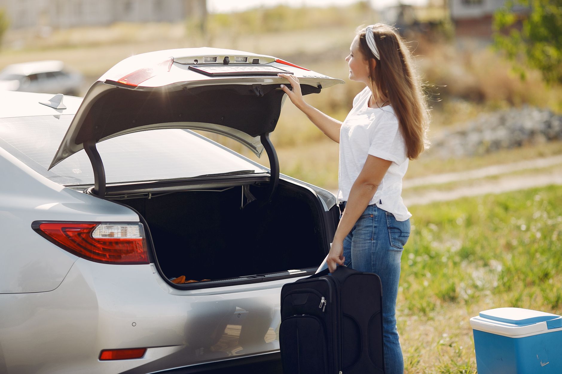 family loading suitcase and dog into car for road trip