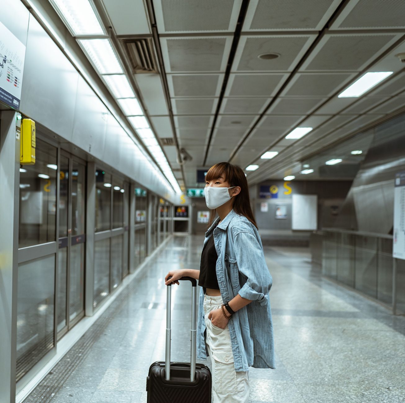 woman holding small dog carrier at airport terminal