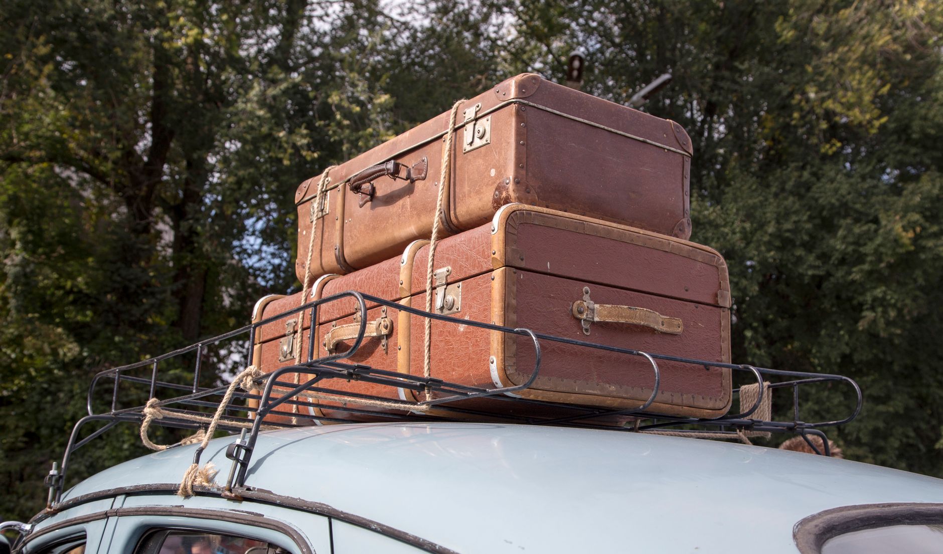 family loading suitcase and dog into car for road trip