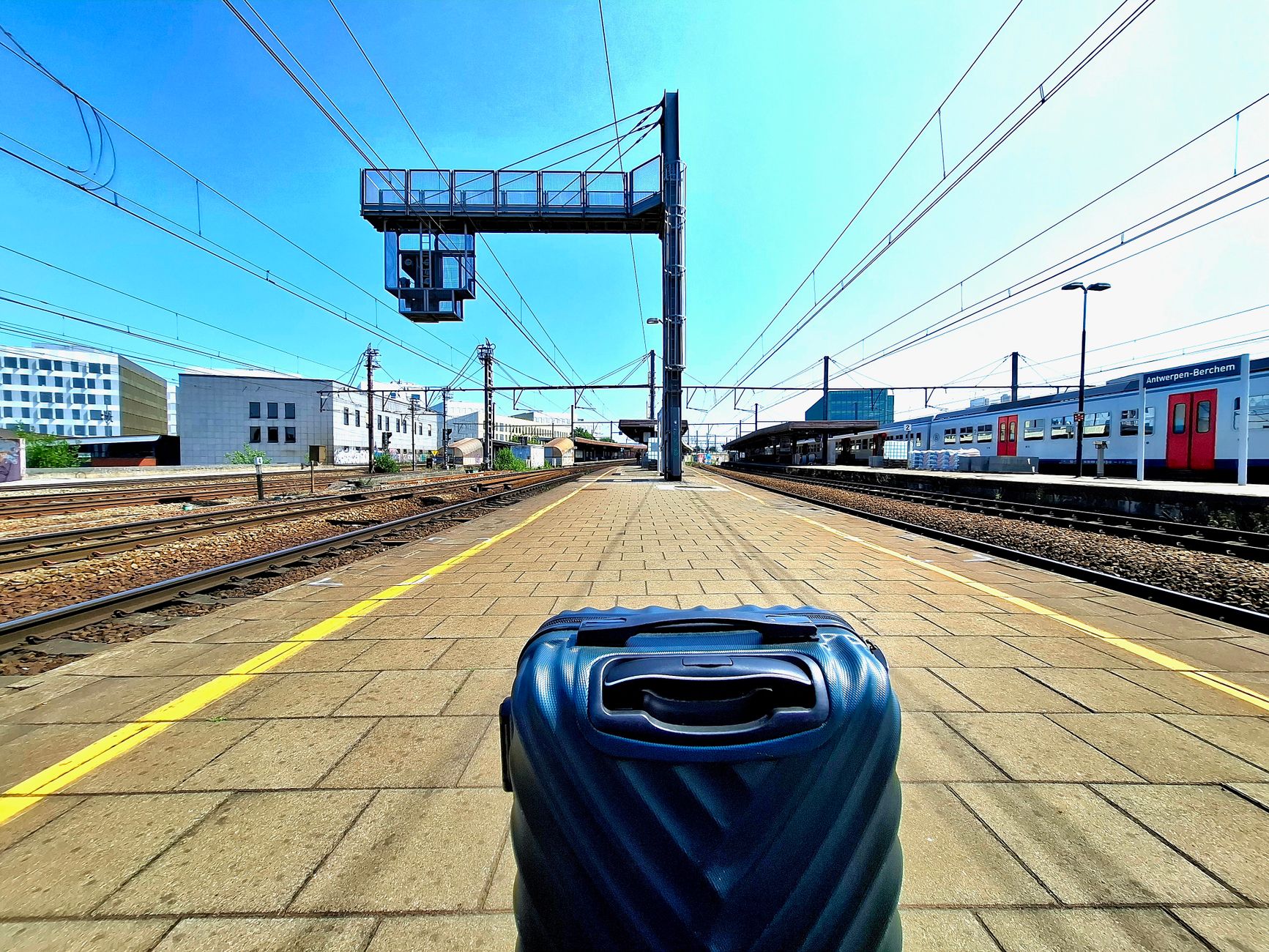 cat travel crate beside suitcase on train station platform
