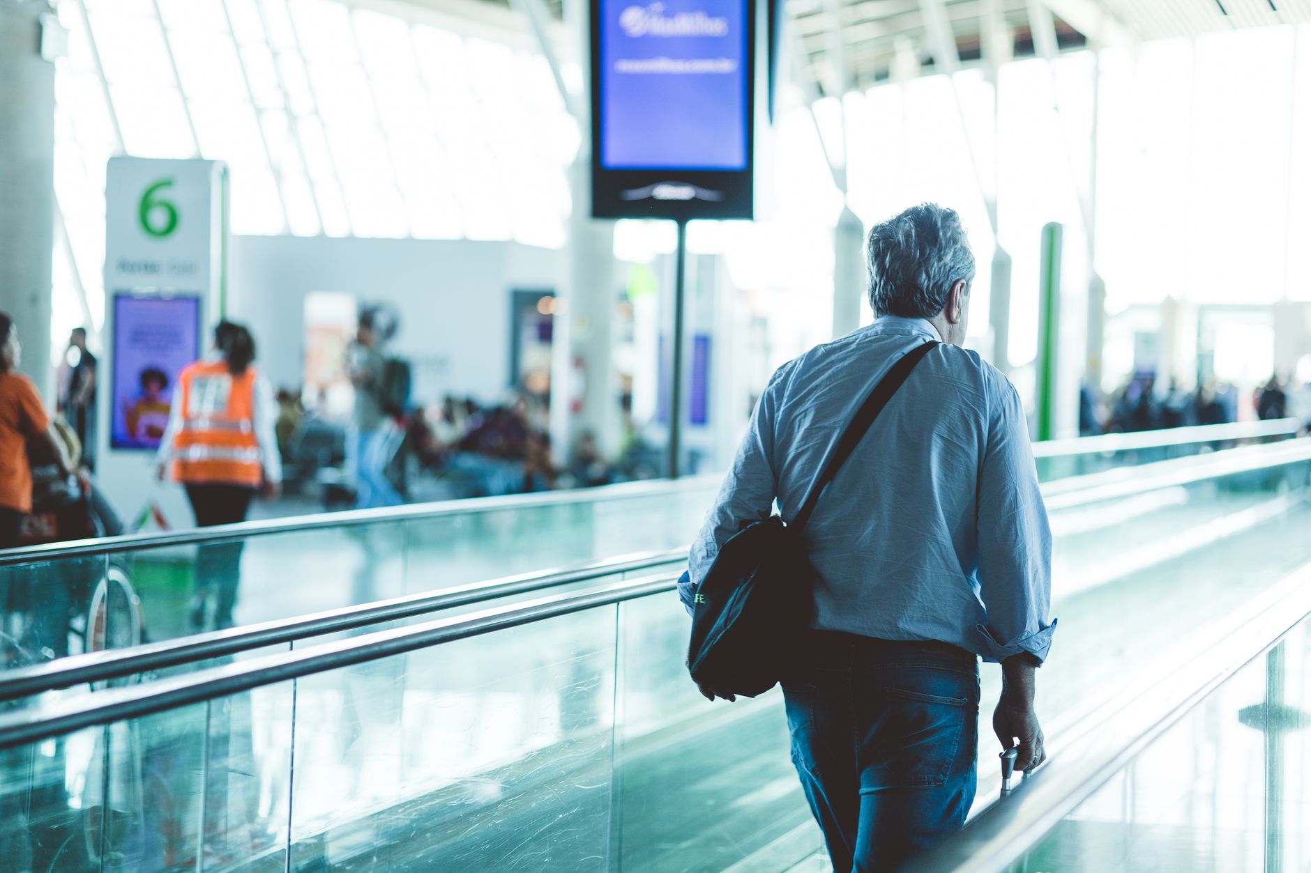 passenger holding pet carrier walking through airport terminal gate
