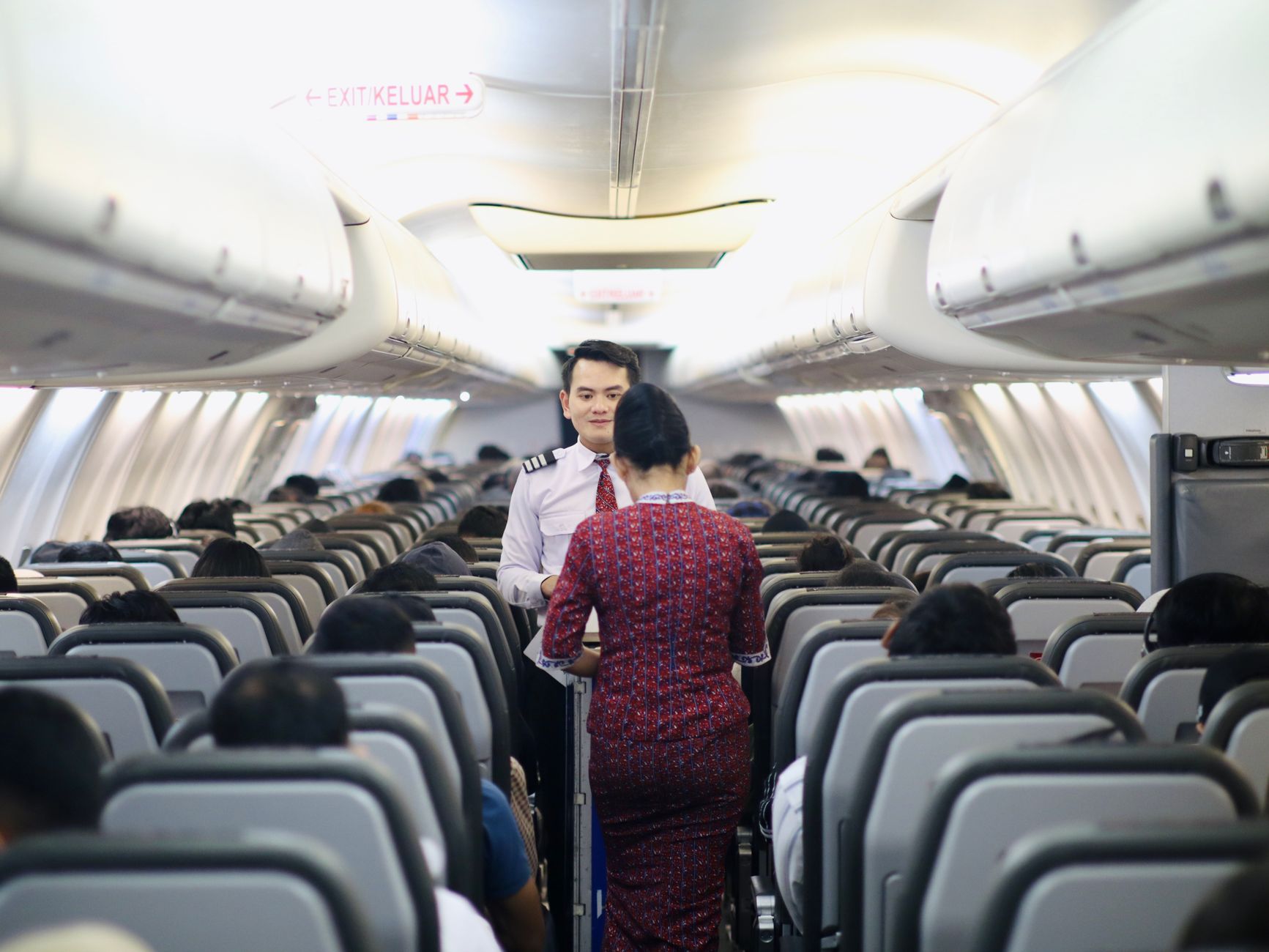 cat carrier next to passenger on airplane cabin aisle