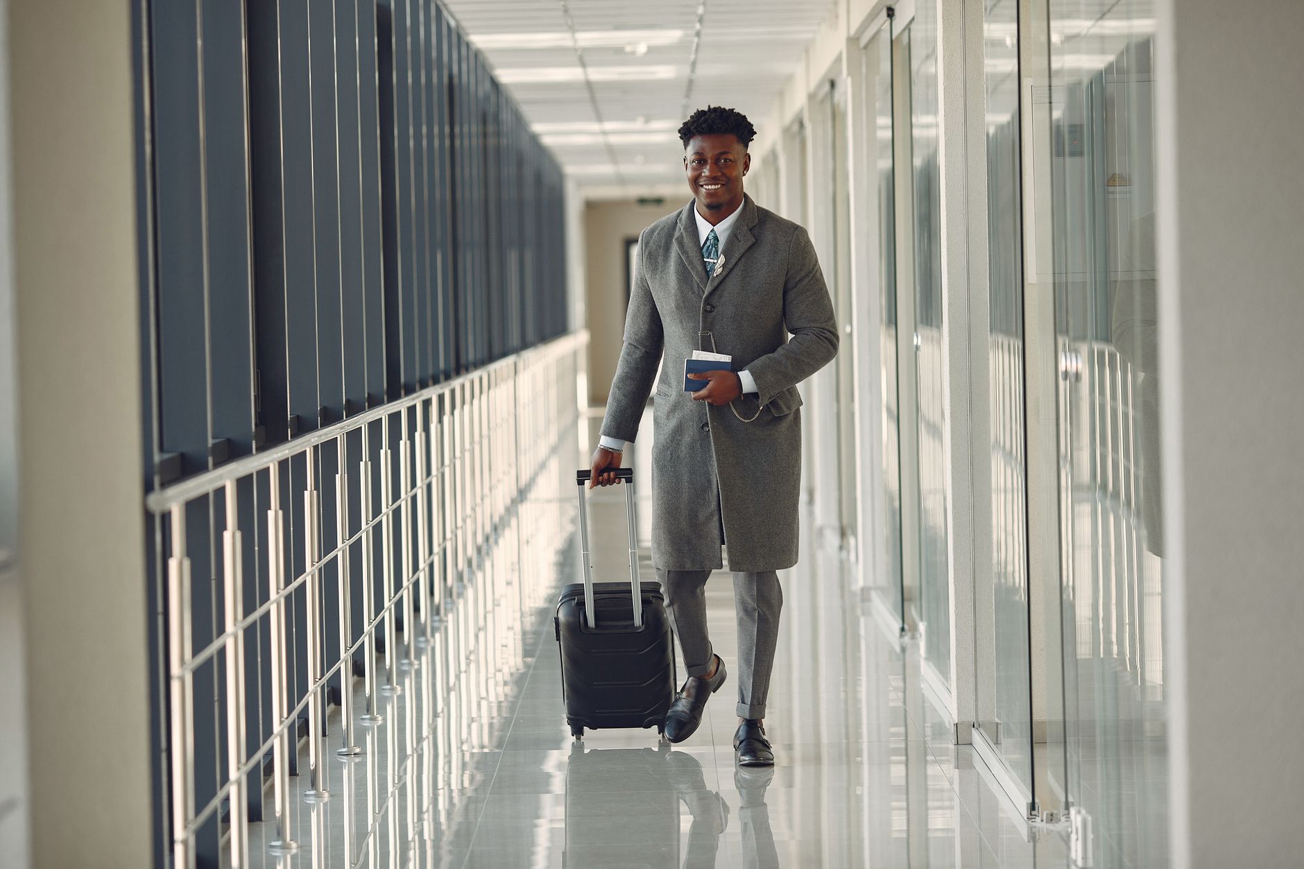 passenger rolling pet carrier through airport terminal corridor
