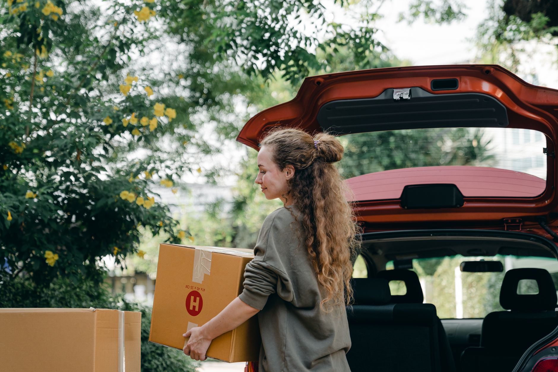person loading dog crate into car trunk driveway moving boxes