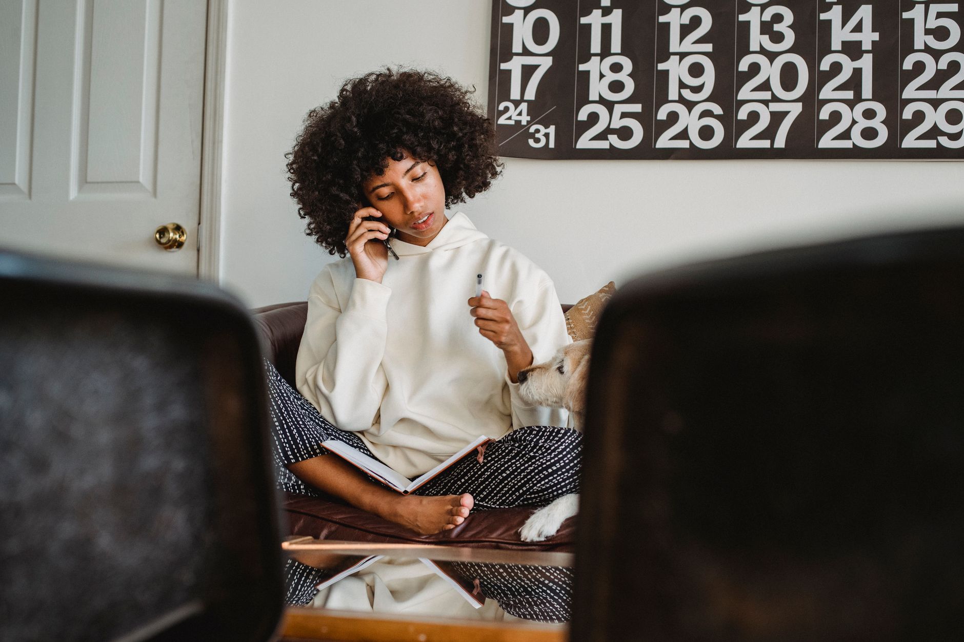 woman calling on smartphone beside empty pet travel crate in living room