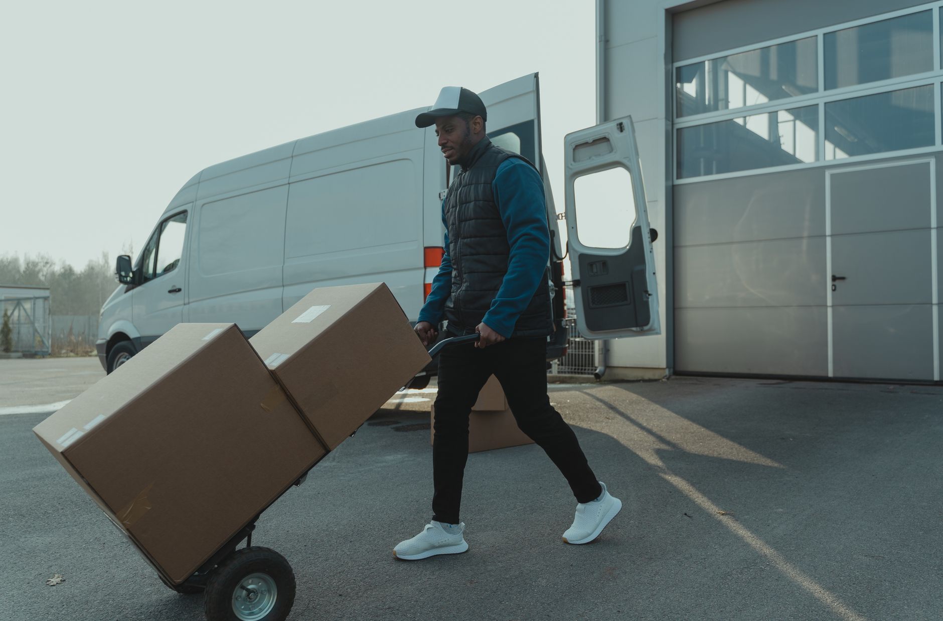 family loading dog crate into moving van driveway