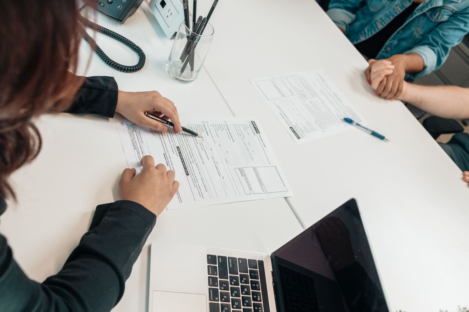 woman filling out paperwork with dog beside her at desk