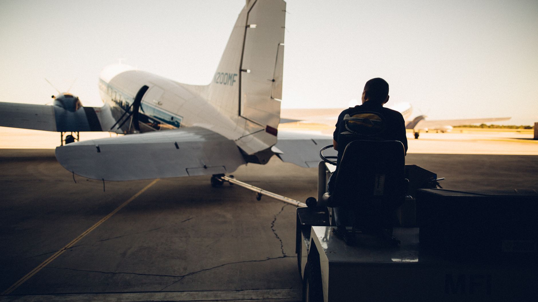 airline cargo worker loading pet crate on tarmac